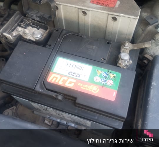 מצבר רכב עם כבלים מחוברים בתא המנוע